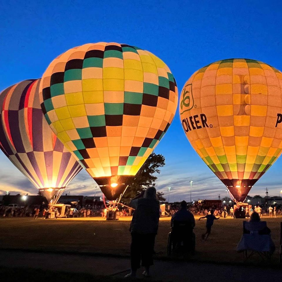 Three hot air balloons on the ground at night with bright blue skies.