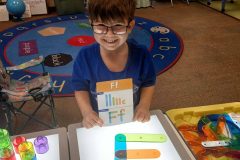 Young child in a classroom playing with light boxes thanks to the early childhood coalition.