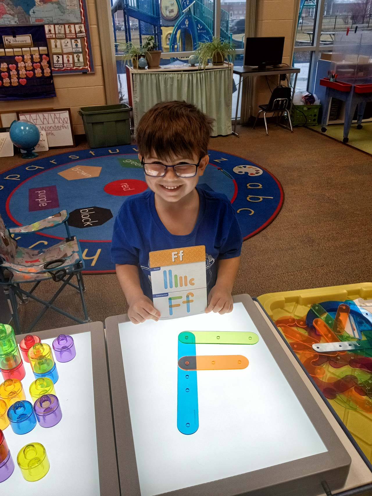 Young child in a classroom playing with light boxes thanks to the early childhood coalition.