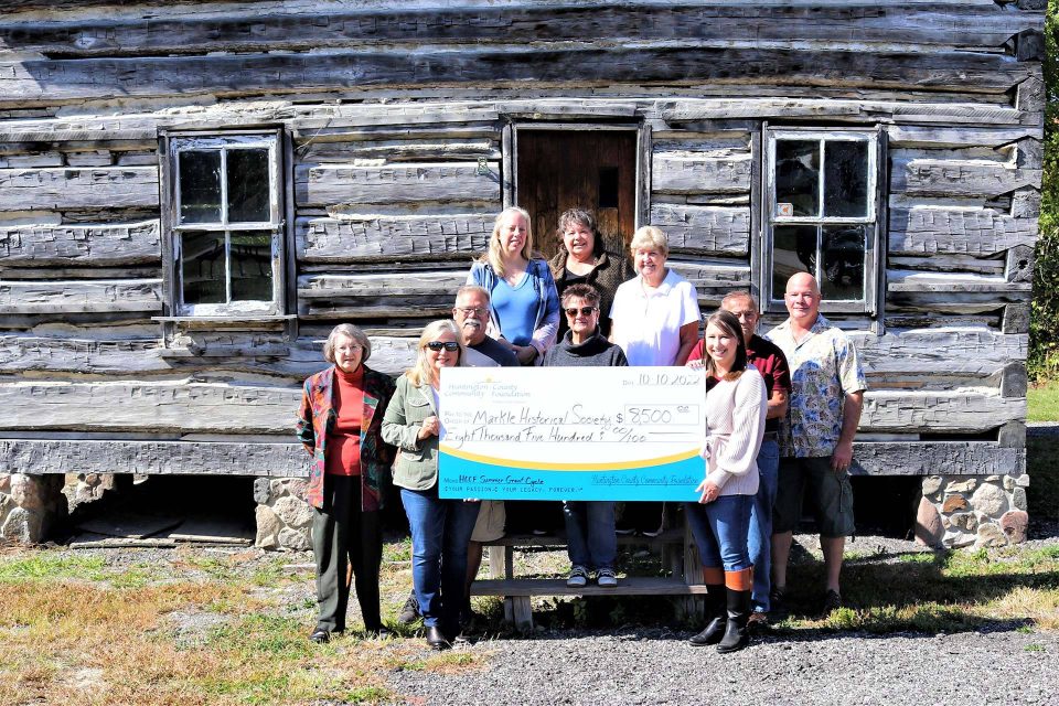 CFHC staff members holding a sign in front of a gray building