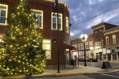 Exterior of Warren Town Hall building with Christmas lights on buildings and trees.