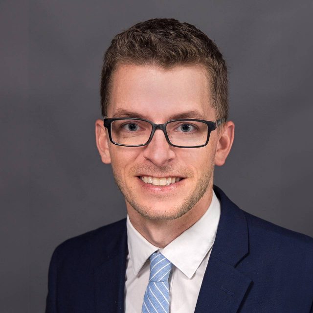 Head shot of Matt Ditzler wearing a dark blue suit jacket and blue tie with a white shirt