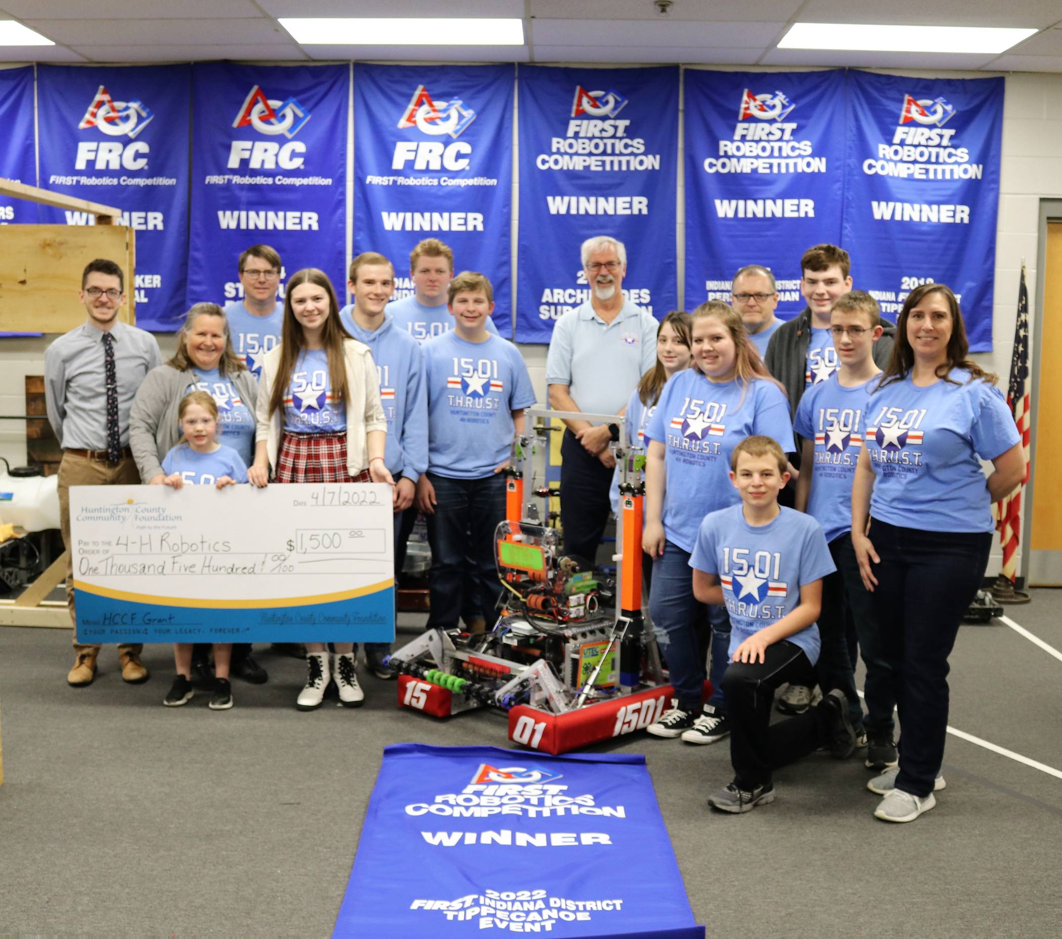 Huntington County 4-H robotics group photo displaying winner banner for 2022 and donation check from the group.