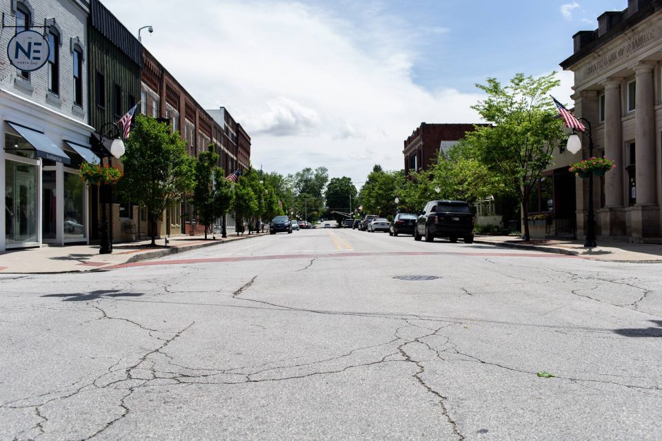 Street view of Roanoke Street with trees and American flags on display.